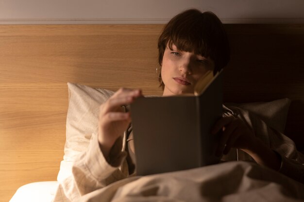 medium-shot-young-woman-reading-bed